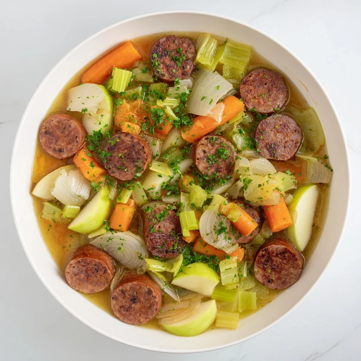 The rich aroma of this stovetop sausage, celery, and apple hotpot simmers in a Dutch oven with apples.