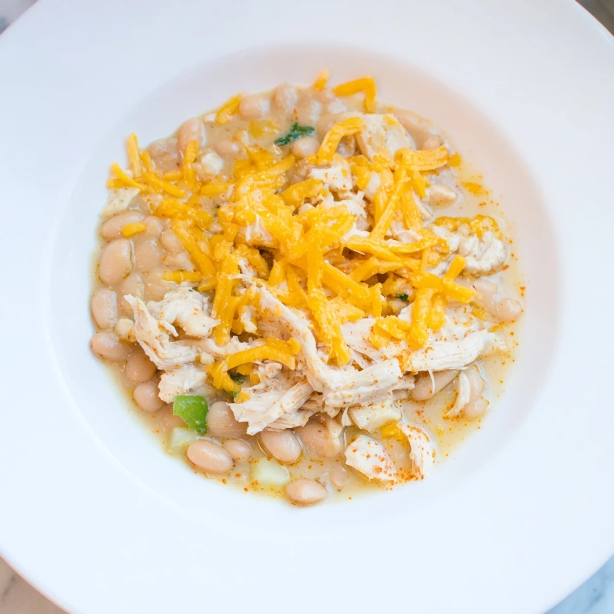 Warm bowl of 35-Minute White Cheddar Apple Chicken Chili, featuring melty cheese and tender chicken.