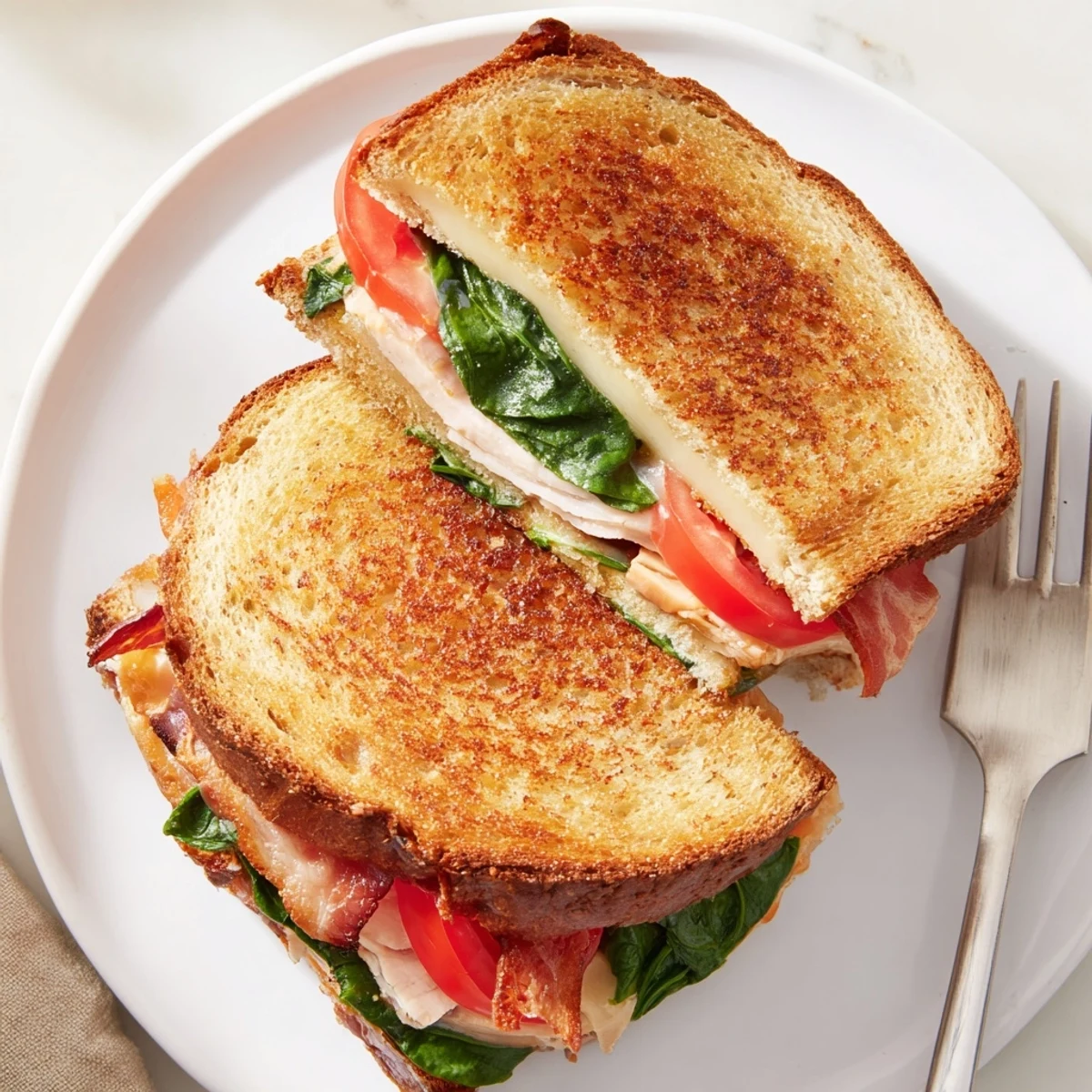 Melted cheddar cheese oozing from a Turkey Bacon, Spinach & Tomato Protein Grilled Cheese sandwich on toasted bread.