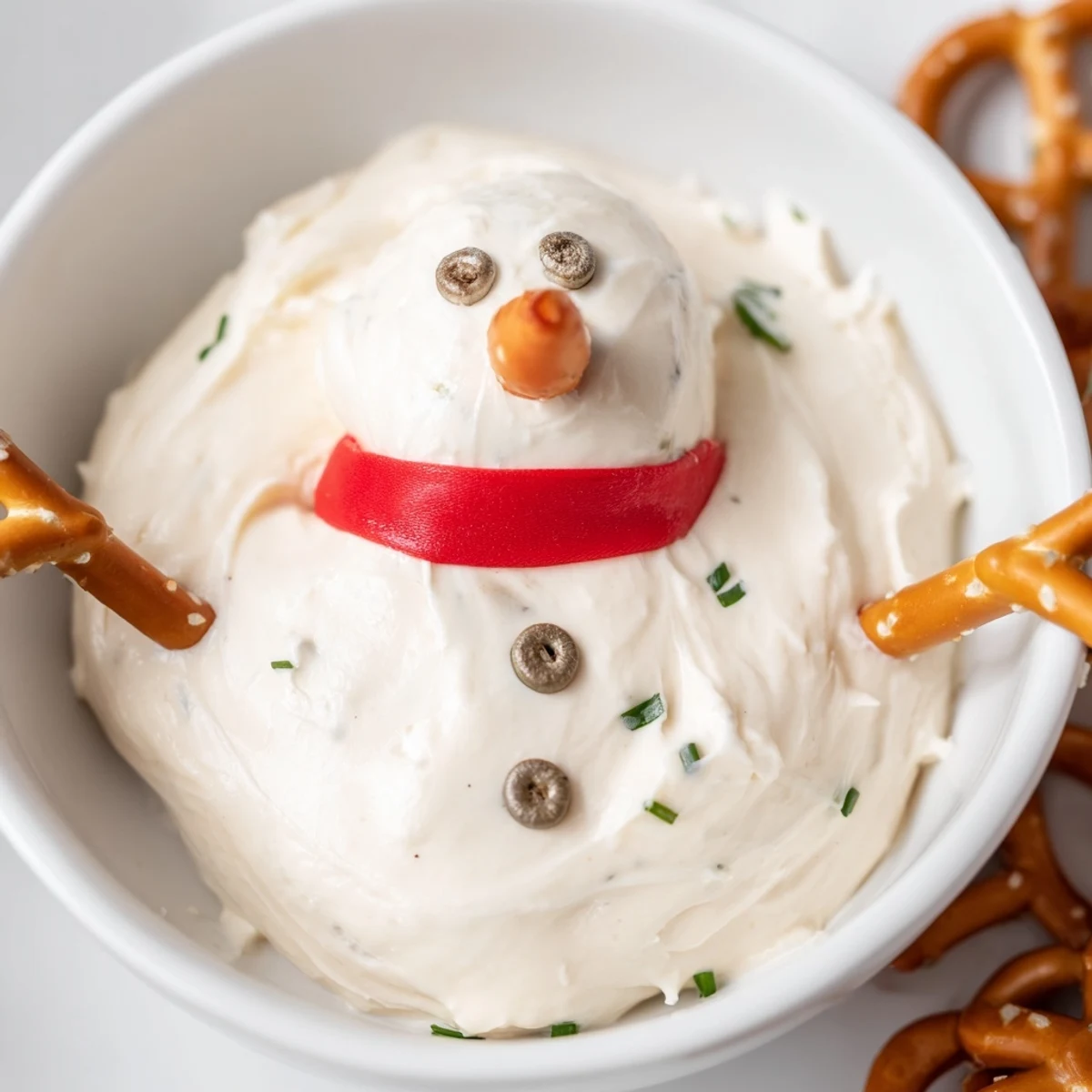 Melted Snowman Dip, a creamy, whimsical appetizer ready with carrot noses and pretzel arms.