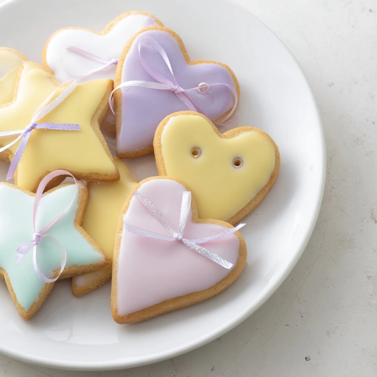 Golden-edged Mignonneries Coeurs et Étoiles Rubans cookies, heart and star shapes, tied with pink ribbons.