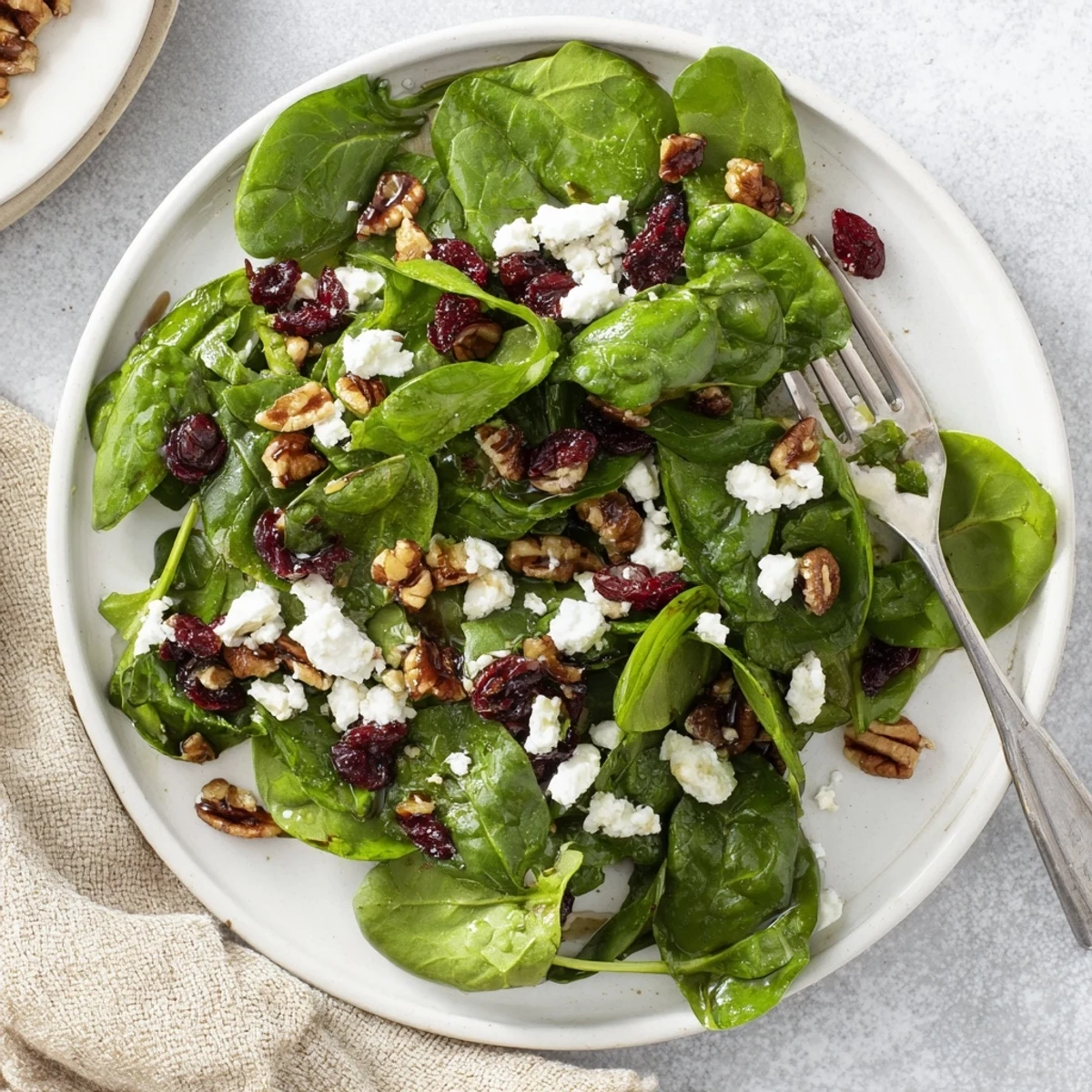 Tender baby spinach and creamy crumbled goat cheese are topped with sweet dried cranberries and candied pecans in this vibrant Spinach Goat Cheese Salad.  