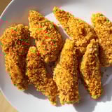 Enjoy a plate of flavorful buttermilk fried chicken tenders served hot with a side of coleslaw.