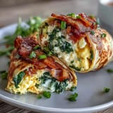 Nutritious green eggs and ham breakfast wraps featuring soft scrambled eggs, diced ham, melted cheddar, and baby spinach rolled in spinach tortillas.