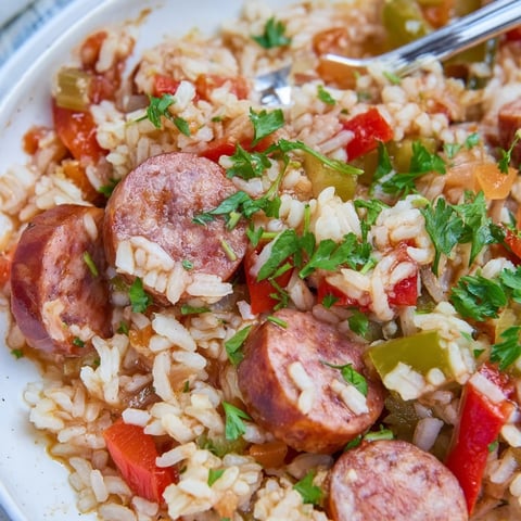 Juicy one-pot sausage and rice skillet garnished with fresh parsley, perfect for weeknight meals.  