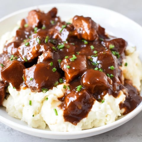Tender bites of apple cider beef stew atop cheddar mashed potatoes, a comforting fall classic.