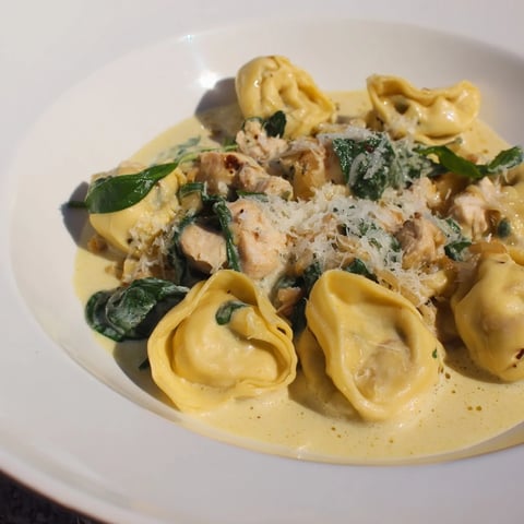 Creamy Chicken and Spinach Tortellini, a rich pasta dish, tossed with Parmesan and fresh herbs.