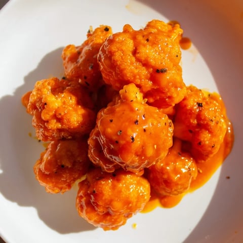 Golden, crispy Buffalo Cauliflower Bites, coated in spicy sauce, ready for a satisfying appetizer.