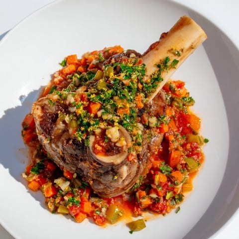 Tender veal shanks of Osso Buco simmering in a rich tomato sauce, ready to serve with polenta.