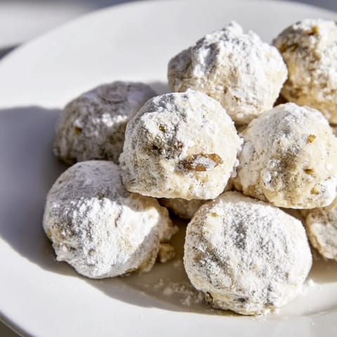 In this photo: a stack of freshly baked Budget-Friendly Snowball Cookies, ready to eat with a warm drink.