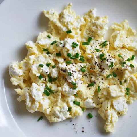 Creamy Cottage Cheese Scrambled Eggs, cooked in butter, pictured with fresh chives for garnish.