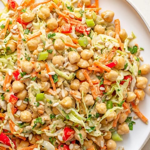 A refreshing bowl of fiber-forward chickpea salad filled with colorful vegetables and tossed in a bright dressing.