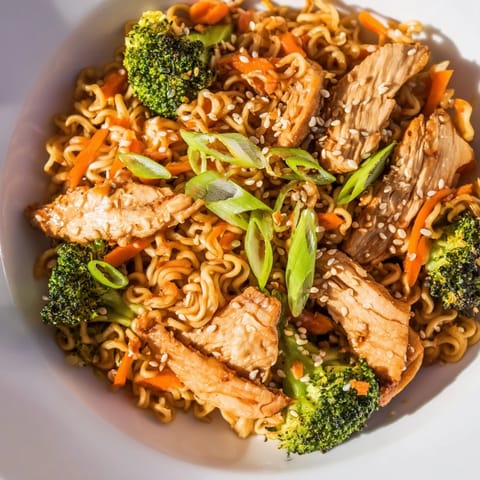 Overhead view of Spicy Ramen Stir-Fry with noodles, crisp broccoli, red peppers, and toasted sesame seeds on a rustic table.  