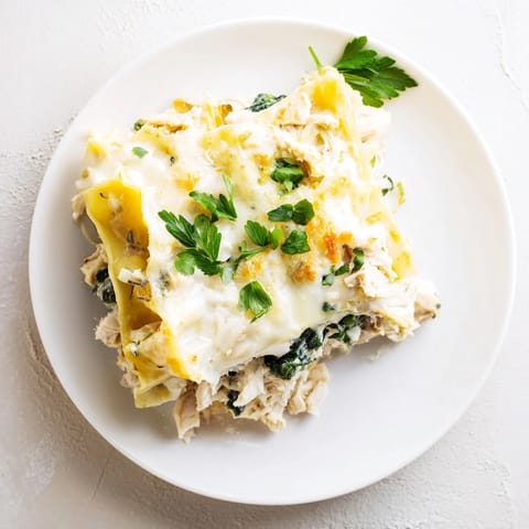 Golden-brown Chicken Alfredo Lasagna rests on a rustic table, garnished with fresh parsley and Parmesan.