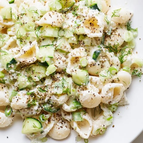 A vibrant bowl of Cucumber Crunch Pasta Salad featuring diced cucumbers, green onions, and crunchy bagel topping.