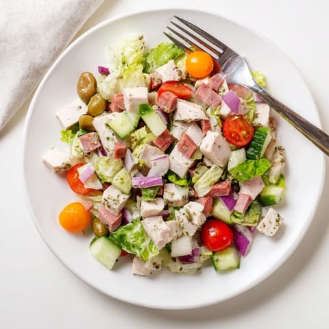 Vibrant Italian Deli Chopped Chicken Salad in a white bowl, topped with pepperoncini and a tangy herb dressing.  