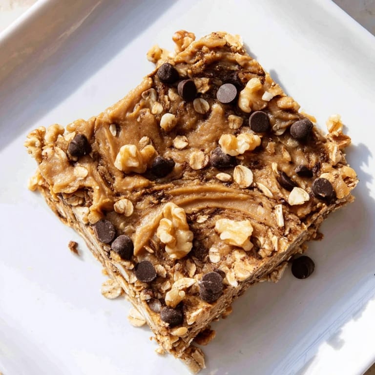 Appealing Peanut Butter Banana Oat Bars, ready to eat, are studded with chocolate chips and banana slices.