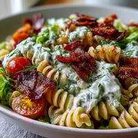 Vibrant BLT pasta salad with crispy bacon, fresh lettuce, cherry tomatoes, and creamy avocado ranch dressing, perfect for summer gatherings.